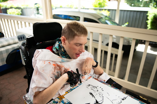 An image of Oliver outdoors using charcoal to draw.