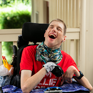 An image of Oliver smiling outside his home.