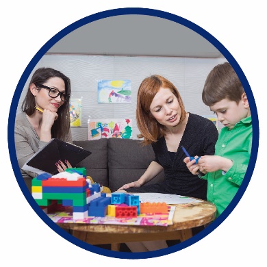 A boy and his mum playing with blocks, while a woman watches and writes something on a clipboard