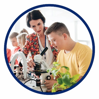 A teacher helping a boy use a microscope in a science class