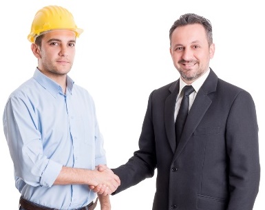 A man wearing a suit, shaking hands with a man wearing a construction hard hat