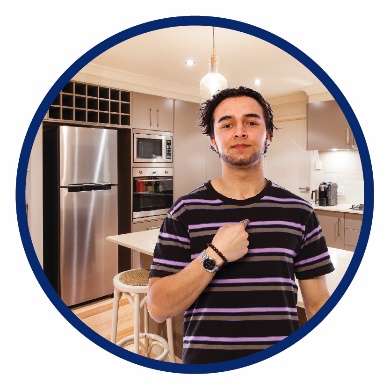 A man standing in a kitchen pointing to himself