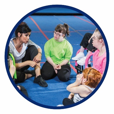 A group of kids sitting in a gym with a teacher