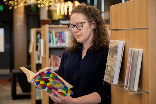 An image of Fiona reading a book in a library