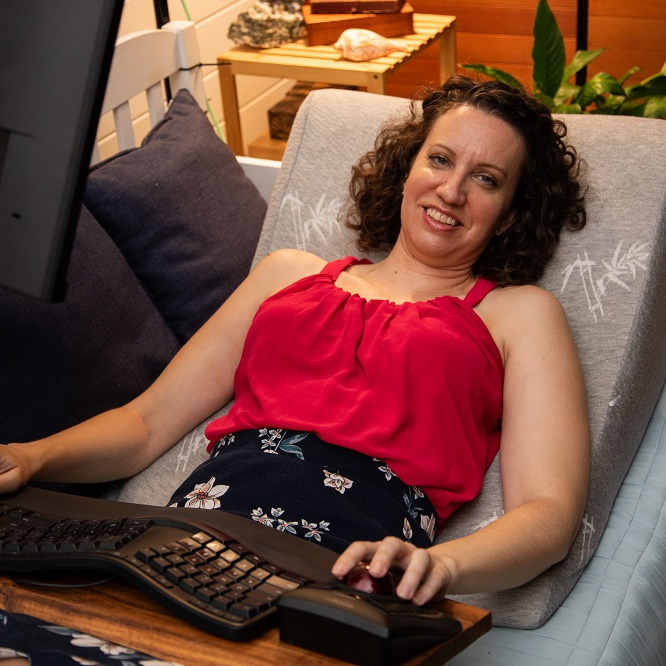 An image of Grace lying down with her remote work set up