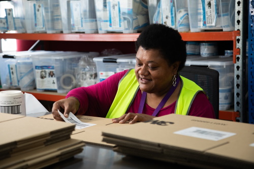 An image of Lowami at work, sticking a label onto a box.