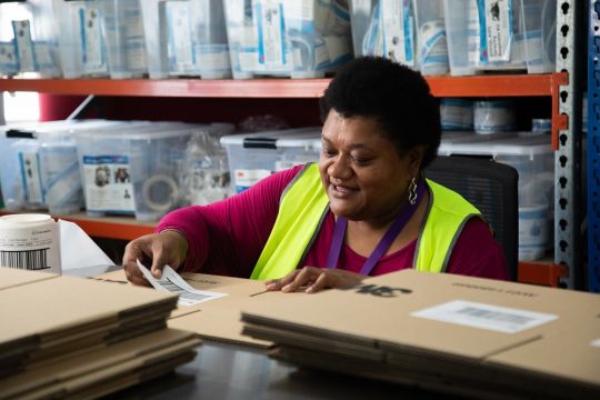 An image of Lowami at work, sticking a label onto a box.